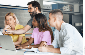 A teacher points to a laptop as students follow along