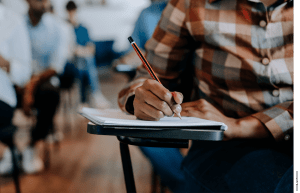 Photo of a man writing in a notebook at a desk