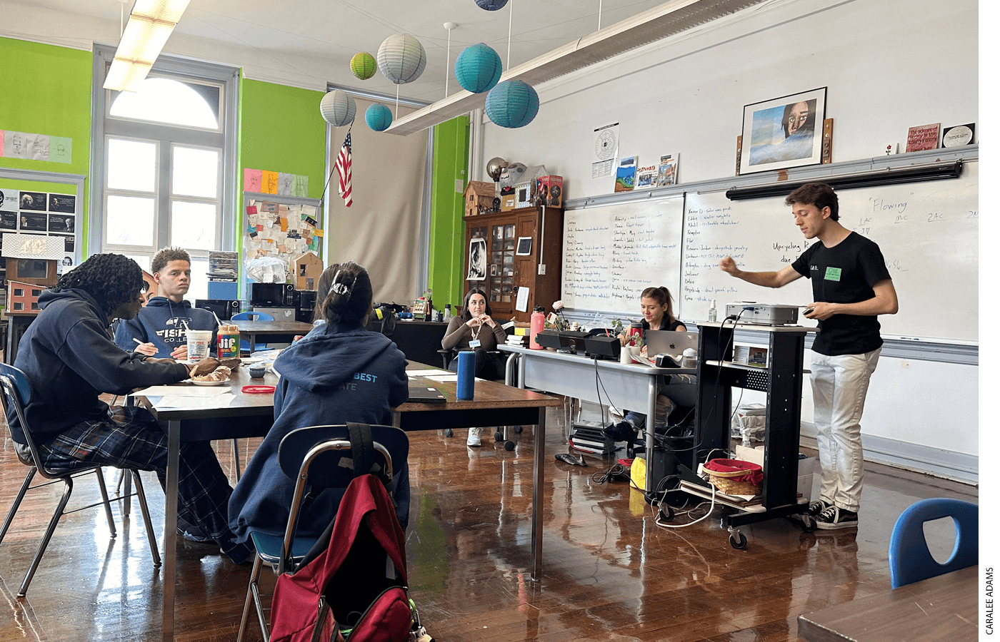 Policy debate teams are guided by coaches who are often debate league alumni, experienced college debaters, or both. Students from Boston Green Academy, with coaches Elise Green and Erica Watson, listen to mentor Jared Aimone share note-taking tips at debate practice.