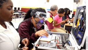 Training for high-tech: In Chattanooga, Tennessee, Tyner Academy students (from left) Jada Beckett and Takayla Sanford work on building circuits, while “mechatronics” teacher Bryan Robinson instructs Brookeana Willams and Noemy Marberry about soldering.