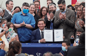 Florida Gov. Ron DeSantis, seated, celebrates after signing a bill that expands eligibility for state scholarships to fund private-school tuition.