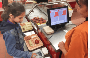 Third grader Eliana Vigil checks out in the lunch line at the Gonzales Community School in Santa Fe.