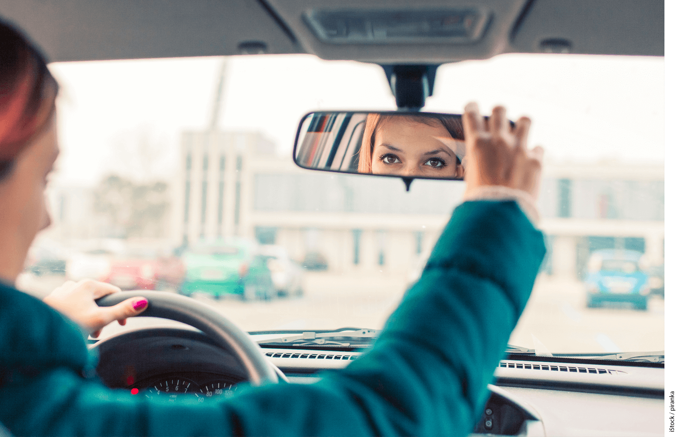 A driver adjusting her rear view mirror