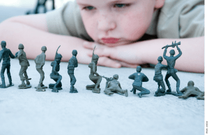 A child looks at a row of little green toy soldiers