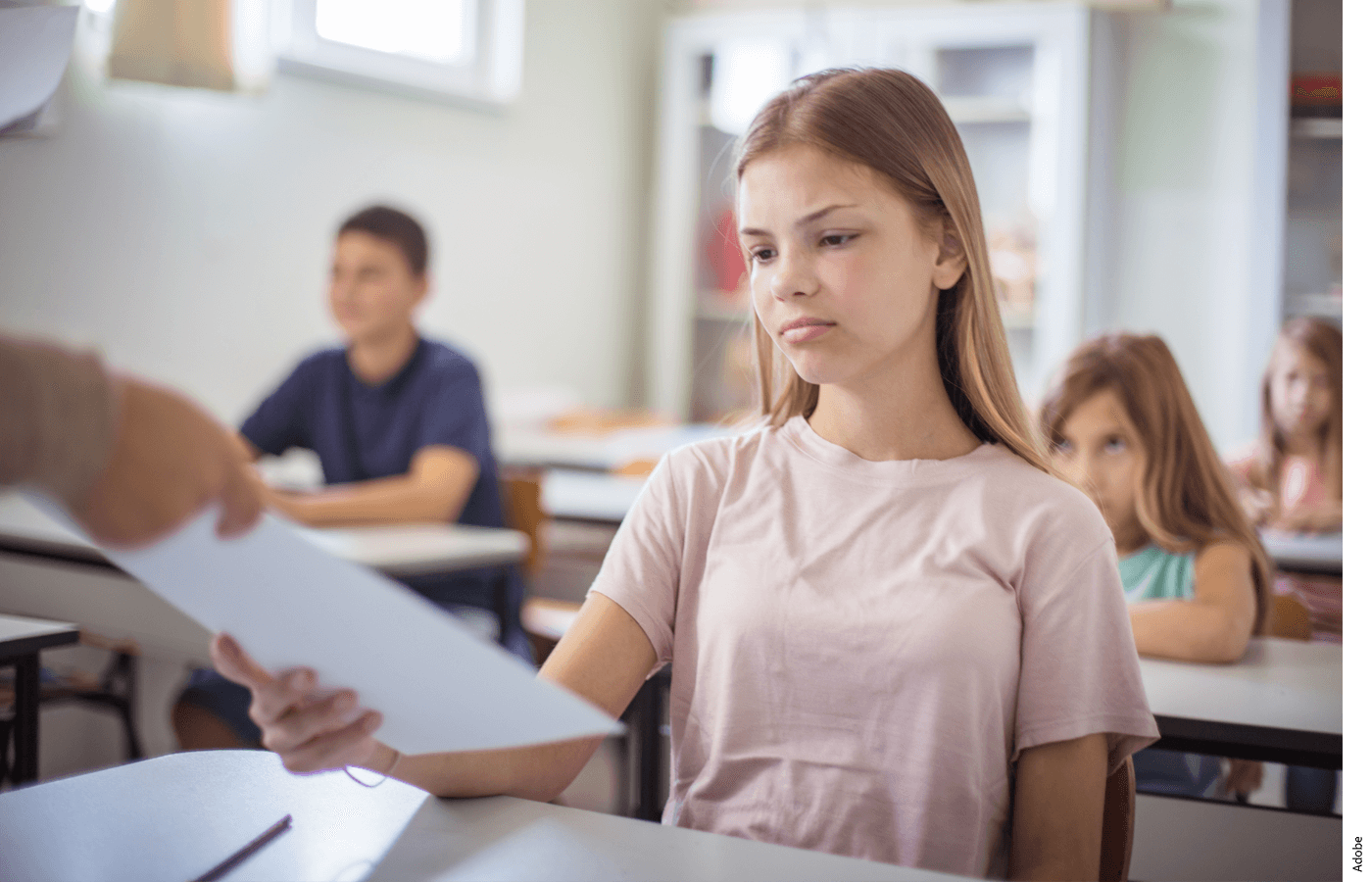 A student is handed a paper by a teacher