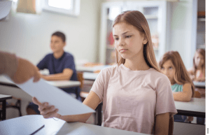 A student is handed a paper by a teacher