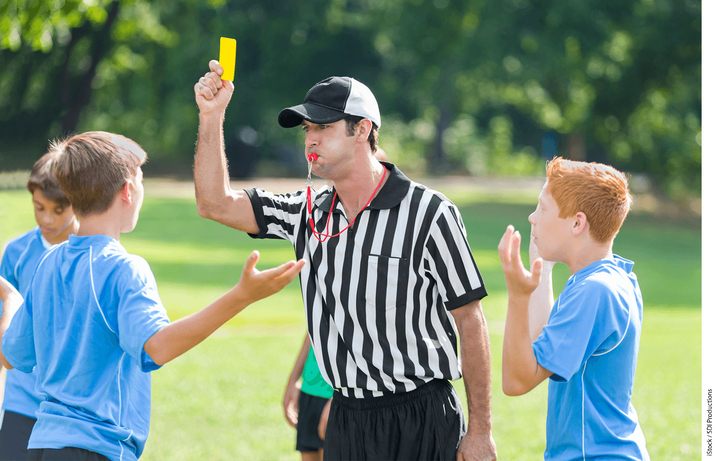 A referee holds up a yellow card in a youth soccer game